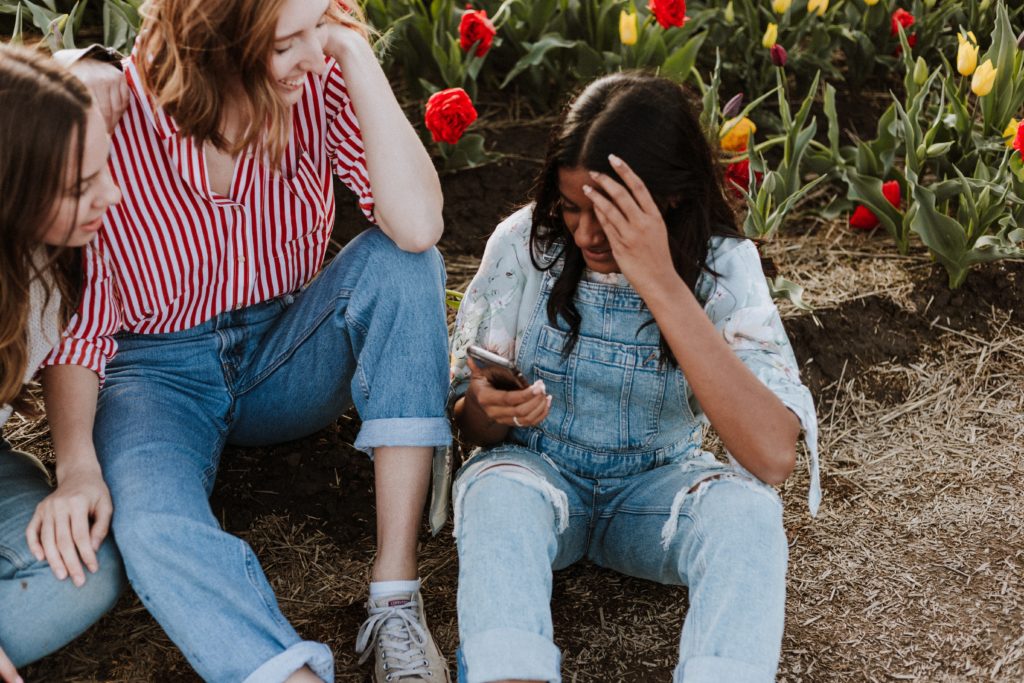 three women laughing while sitting near flowers