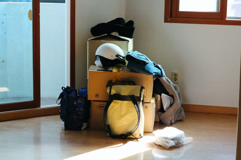 boxes and bags piled upon one another in an empty room