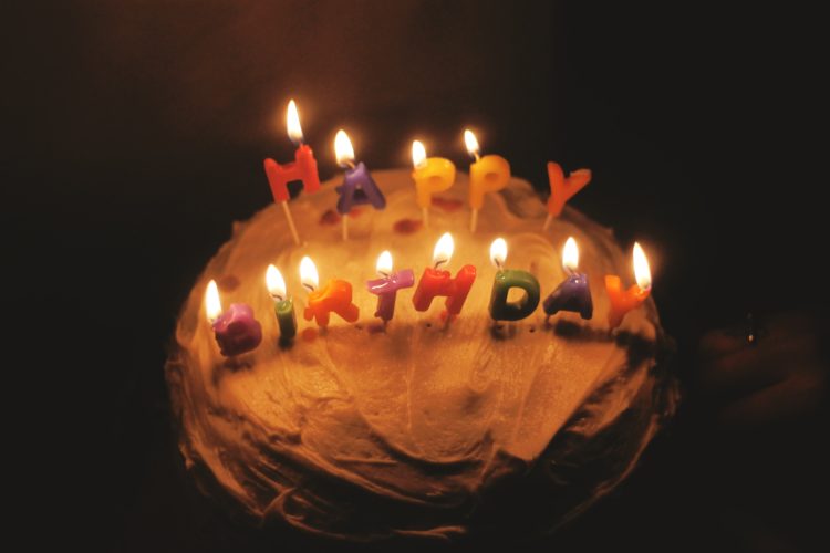 cake with white icing with lit happy birthday candles