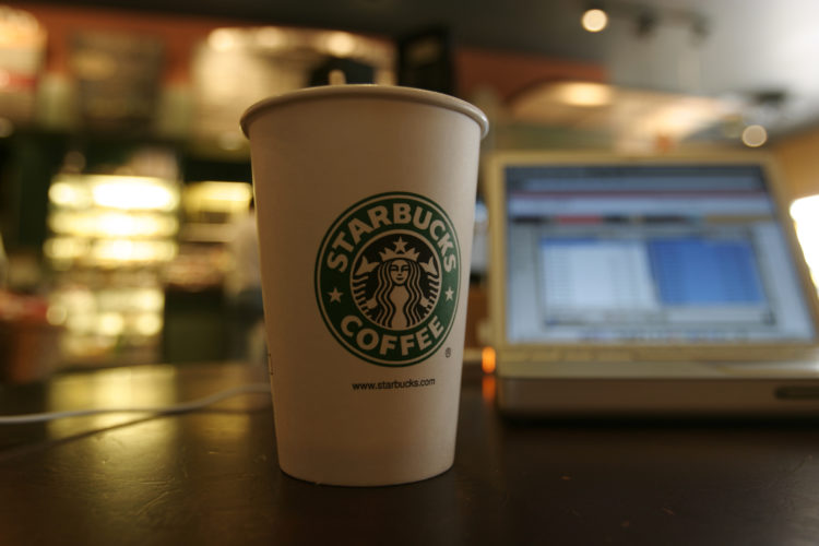 A coffee cup sits next to a laptop connected to the Internet using a Wi-Fi modem at a Starbucks coffee house. Starbucks, in conjunction with the ce...