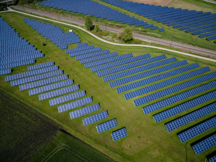 aerial shot of solar panel farm in green field