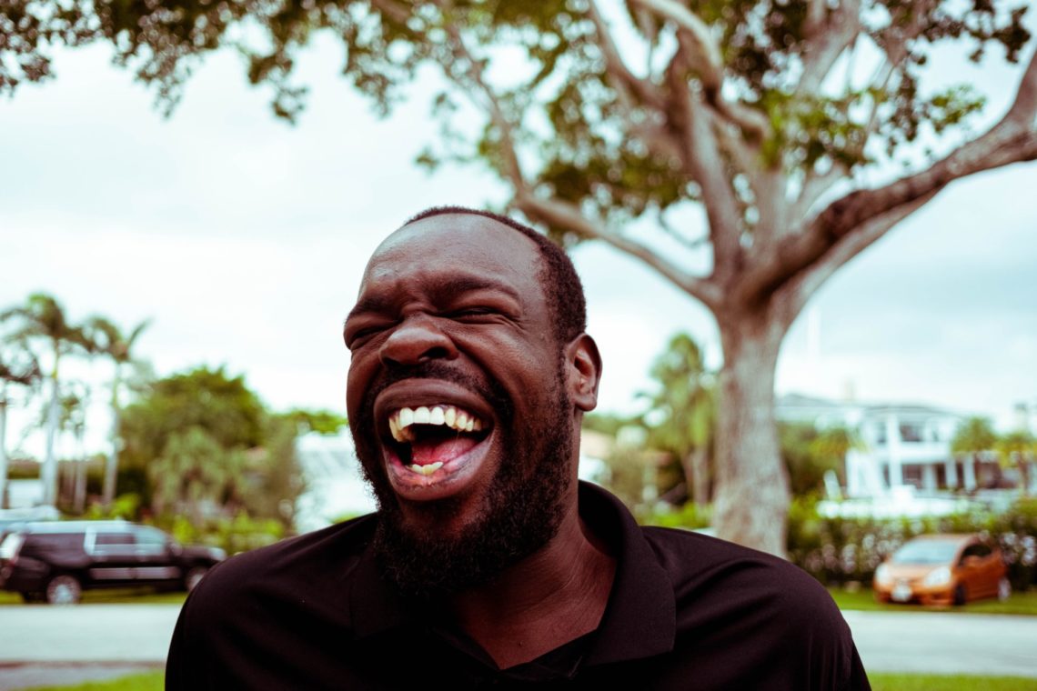 man in black polo shirt laughing oustide