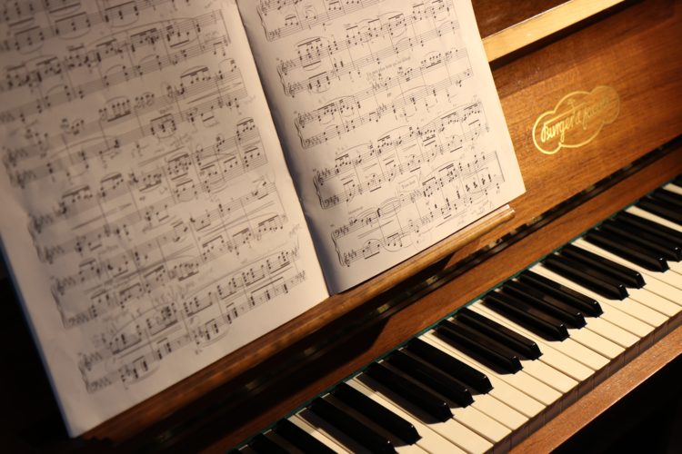 music notes in book balanced on open wooden piano