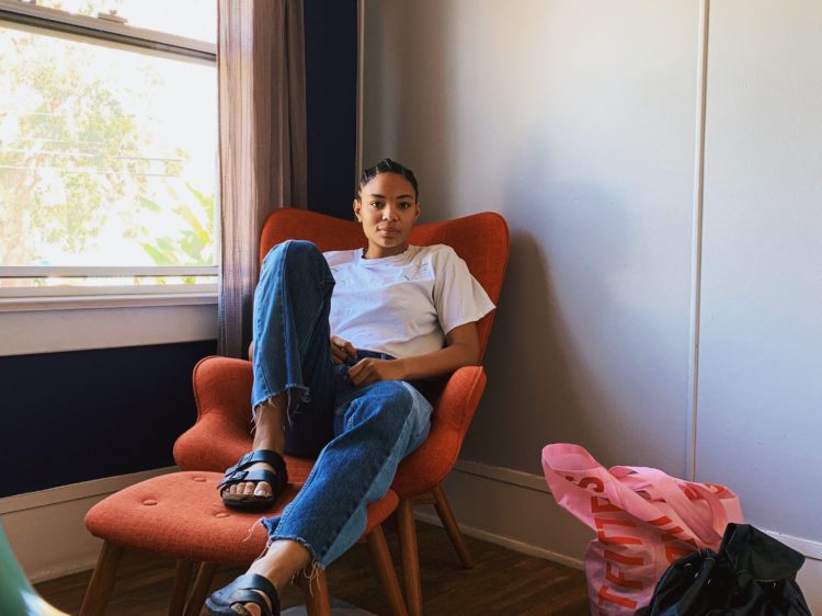 woman sitting on  orange sofa chair beside window looking into camera