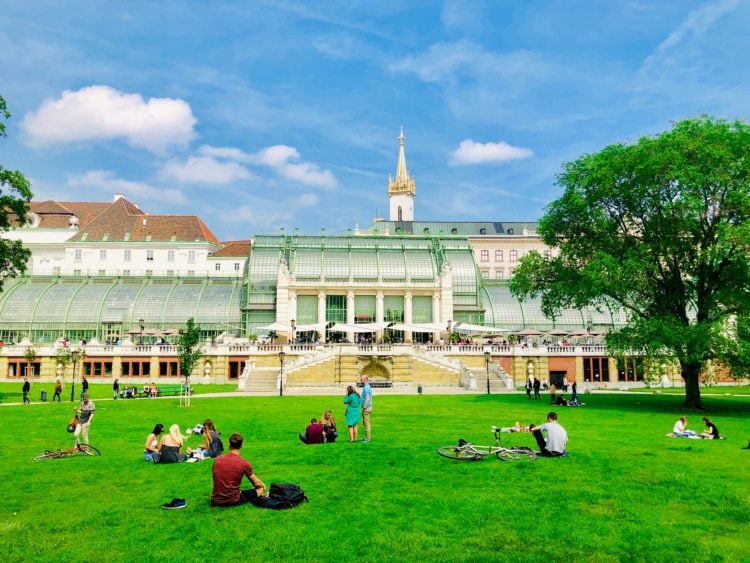 people sitting on green grass field near white concrete building during daytime