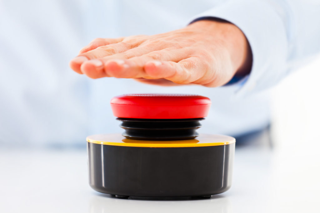 hand hovering over red emergency button