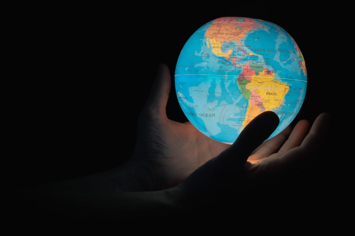 person holding light in shape of planet earth in the dark