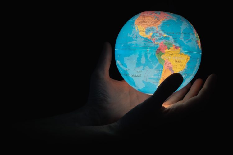 person holding light in shape of planet earth in the dark
