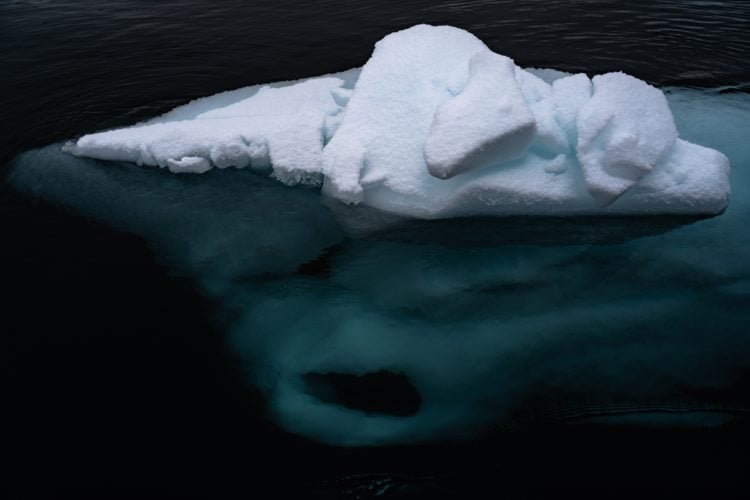 iceberg in dark body of water with some below the surface