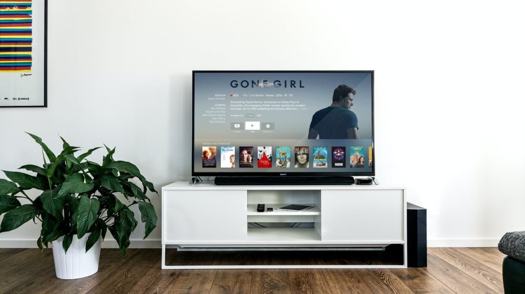 flat screen TV in white minimal living room showing gone girl amongst other films