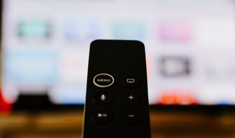 black tv remote in front of blurred tv screen