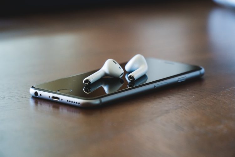 airpods placed on am iphone lying on a wooden table