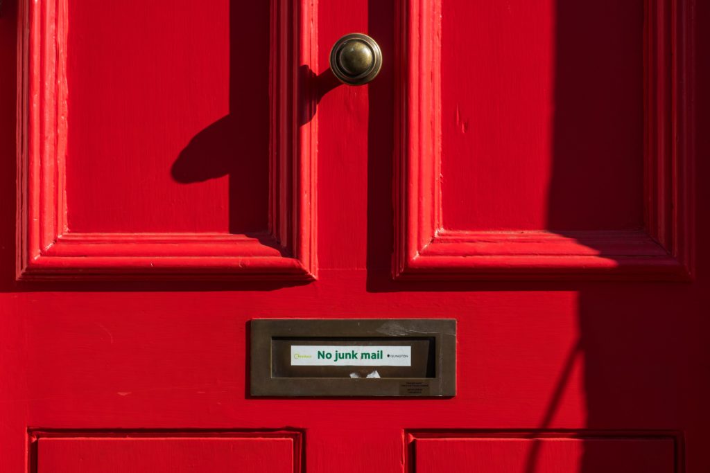 close up of shut red wooden door with 'no junk mail' signn on letterbox