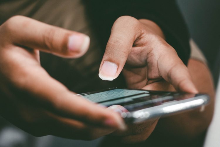 a close up of a person holding a cell phone typing a message