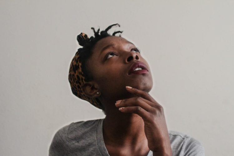 woman in grey top with hand on chin looking up and confused