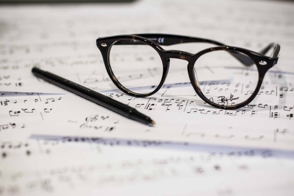 black frame glasses and pen resting on white paper covered in notes