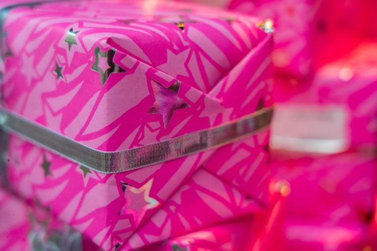 multiple presents wrapped in pink paper with silver stars, with silver ribbon around them