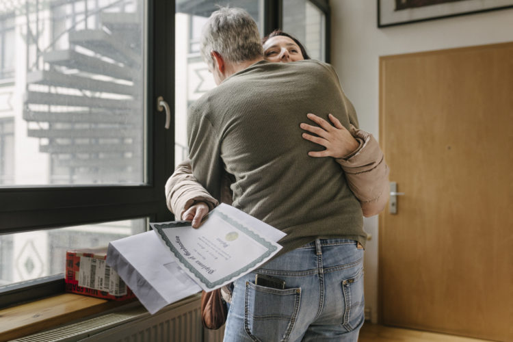 A woman hugging her husband at home after receiving her exam results from her school studies.
