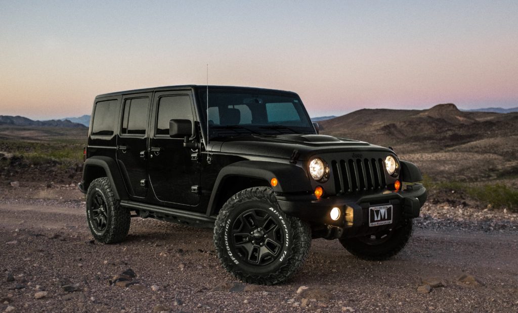 black Jeep Wrangler on dirt road at dusk
