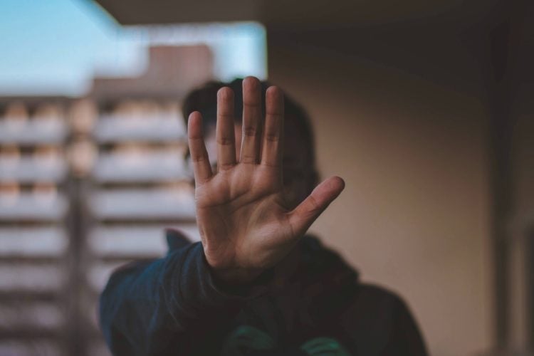 man stood on balcony with open palm facing the camera