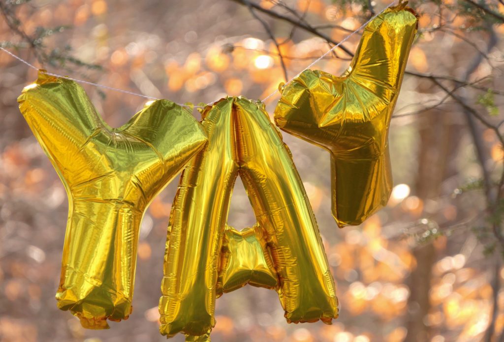 large yellow ballons spelling out YAY hung up on a tree