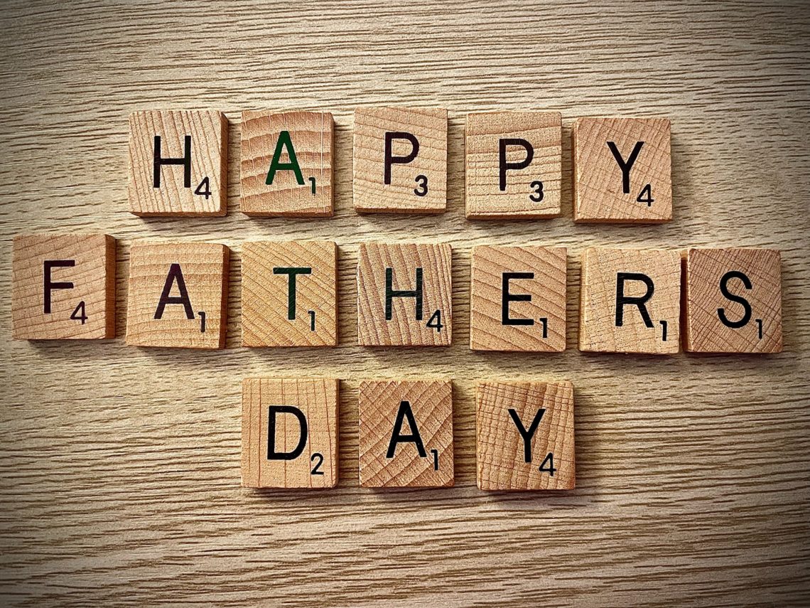 brown wooden letters reading Happy father's Day on wooden background