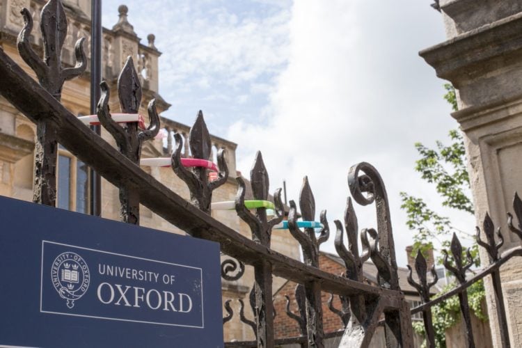 university of oxford sign on fence with building in the