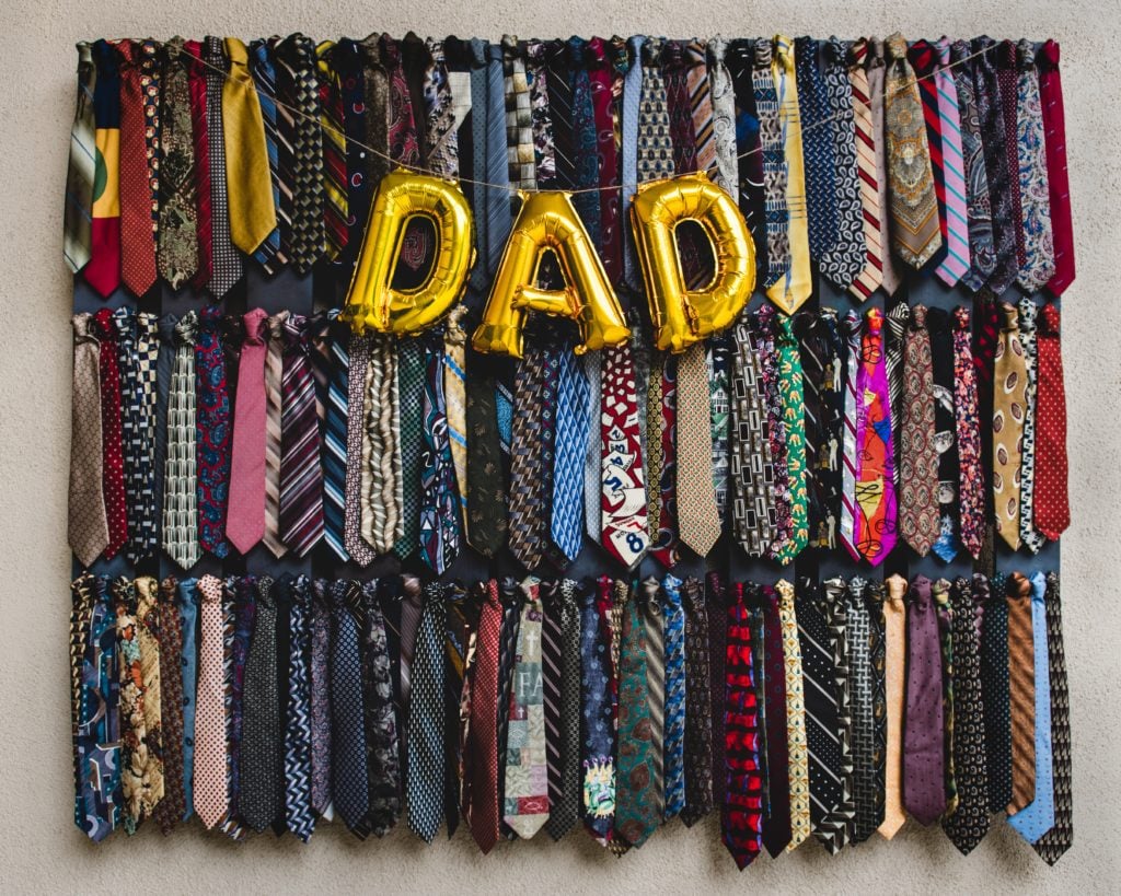 dad written in yellow ballons against a wall covered in various ties